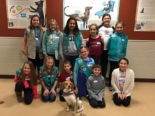 scouts in sashes pose with dog