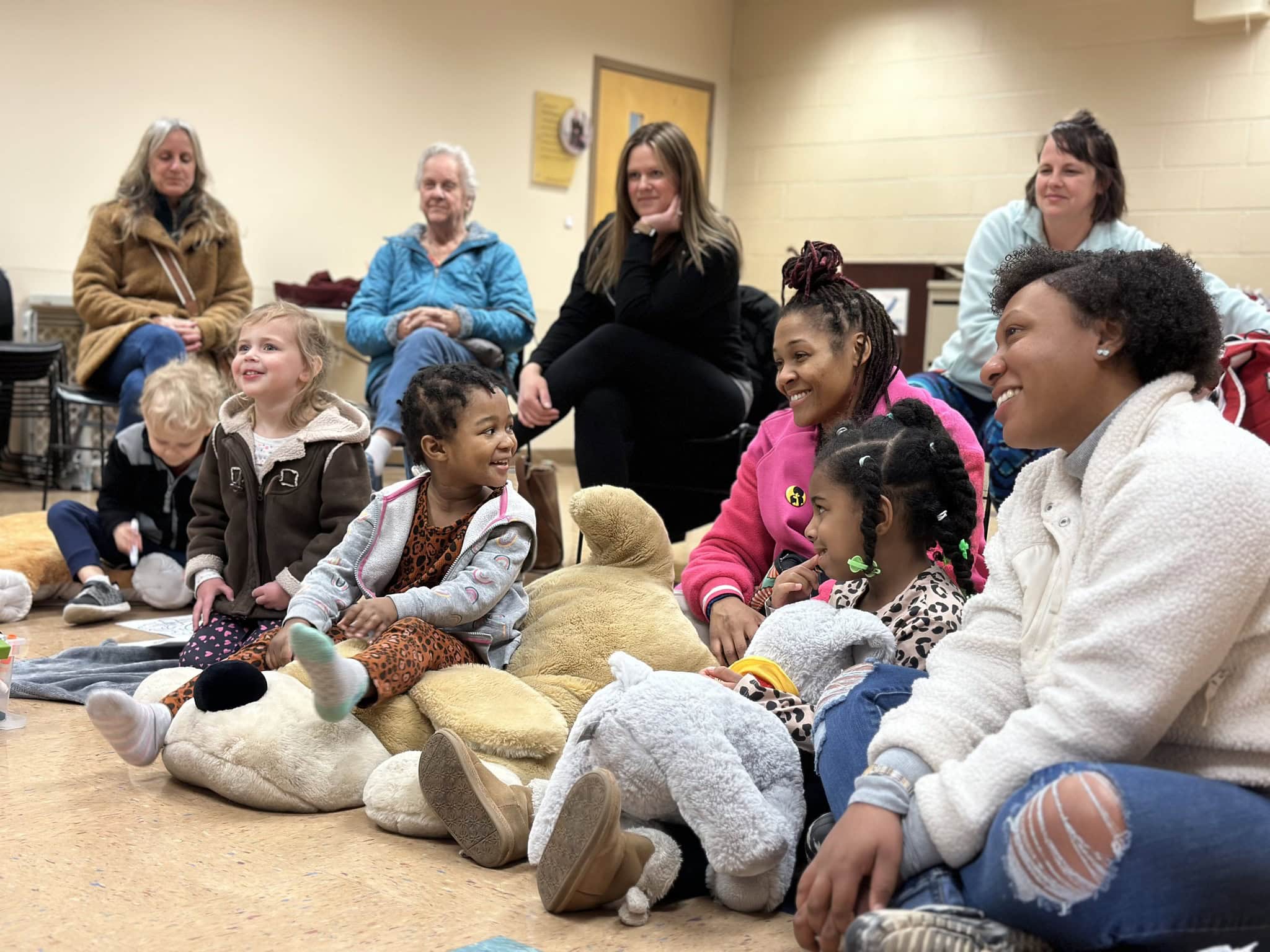 young children and adults sit on floor during story time