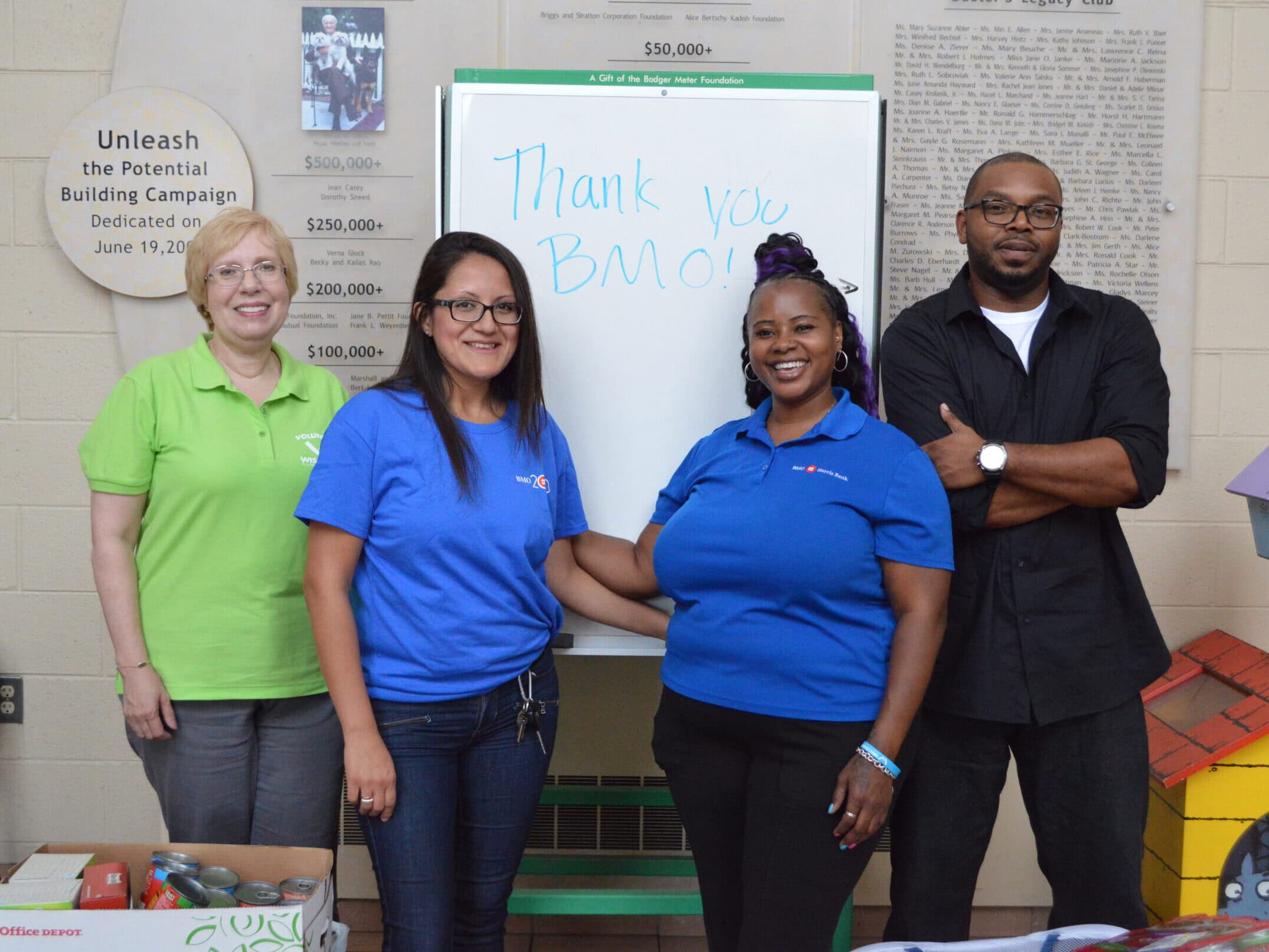 three people stand with a WHS volunteer presenting donations collected for WHS