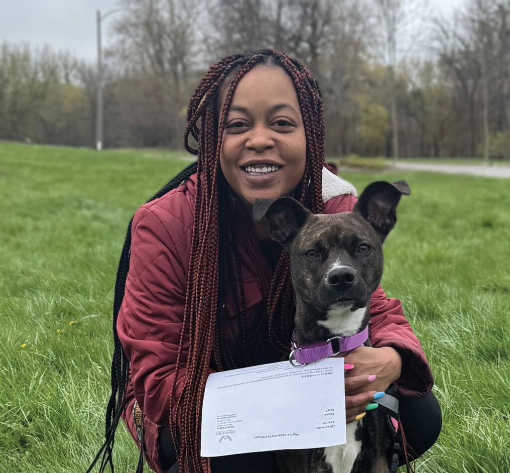 Woman hugs brindle dog and smiles