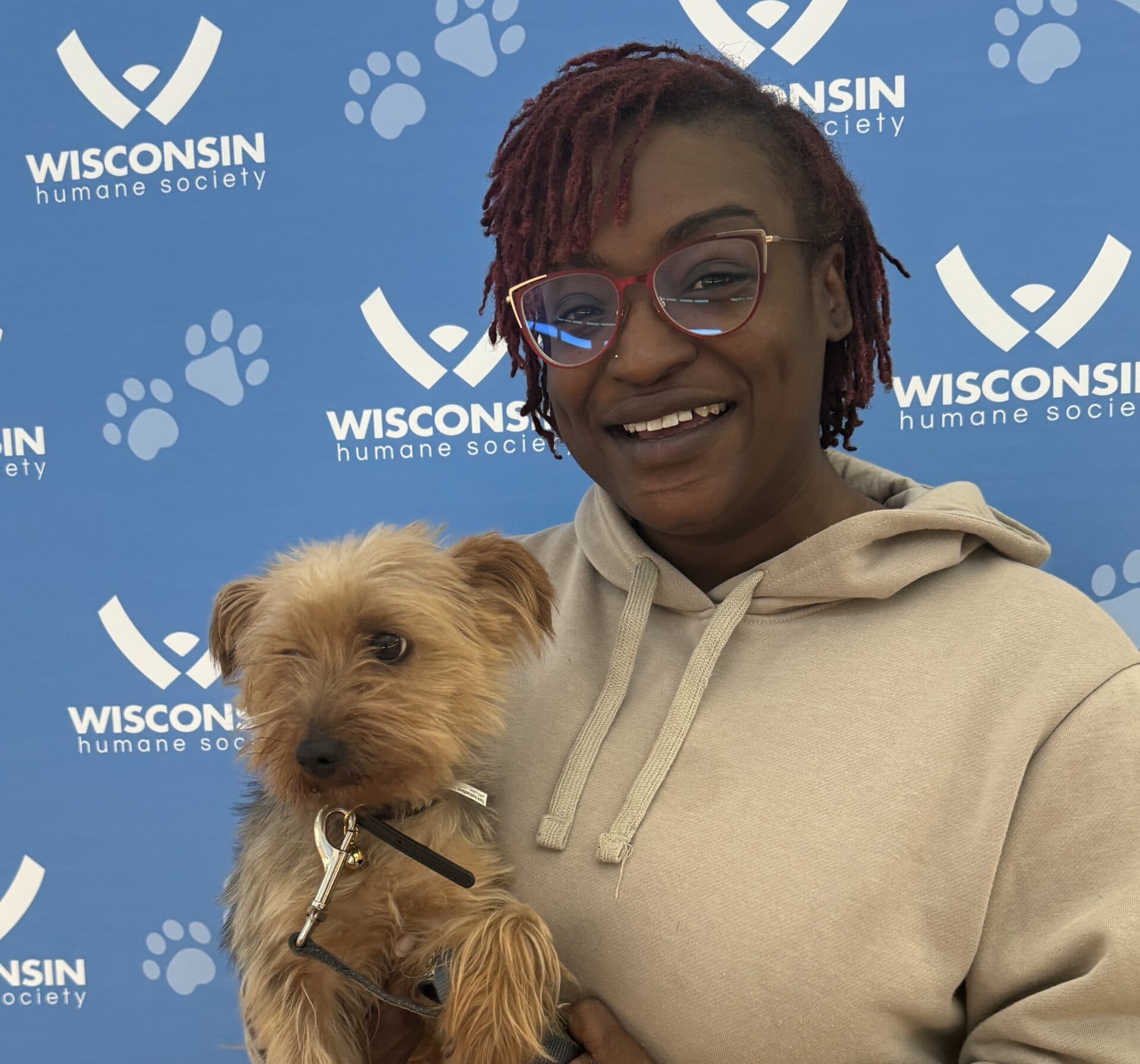 Woman holding small dog in front of WHS backdrop
