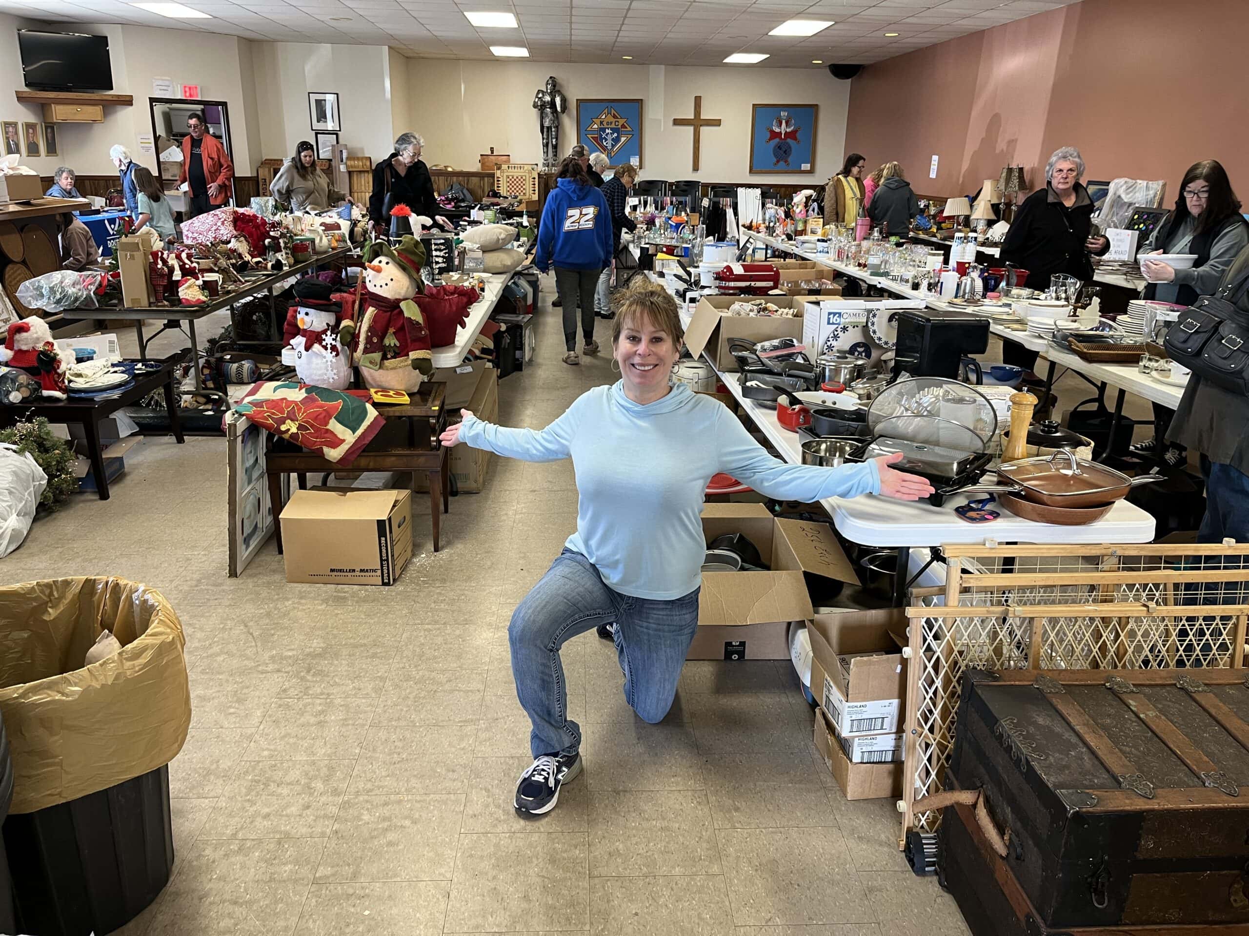 Sharon knealing in front of Door County Rummage Sale items