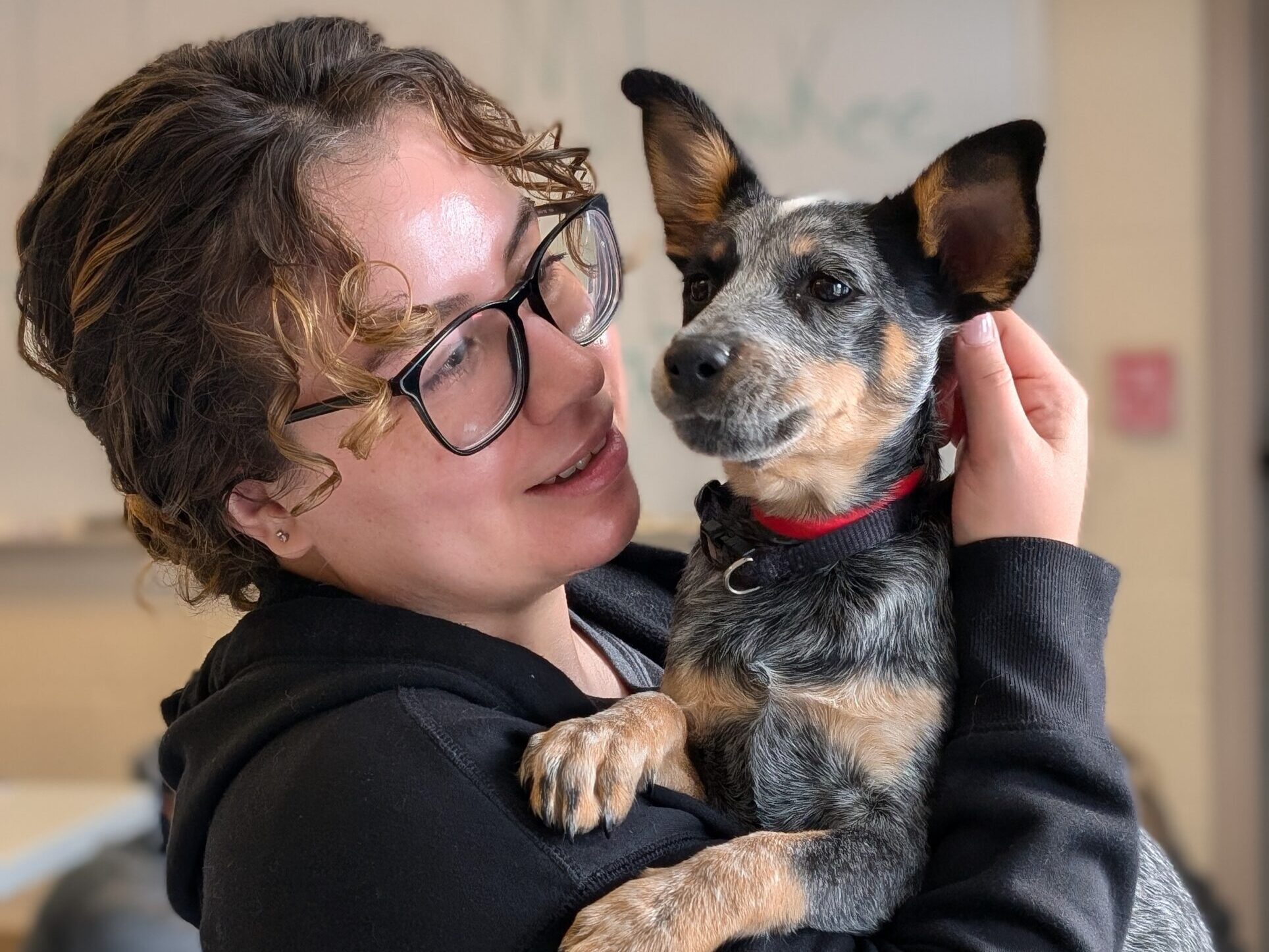 woman with glasses holds puppy in arms