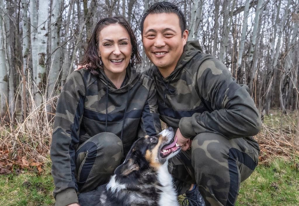 Man and woman with dog smiling outdoors