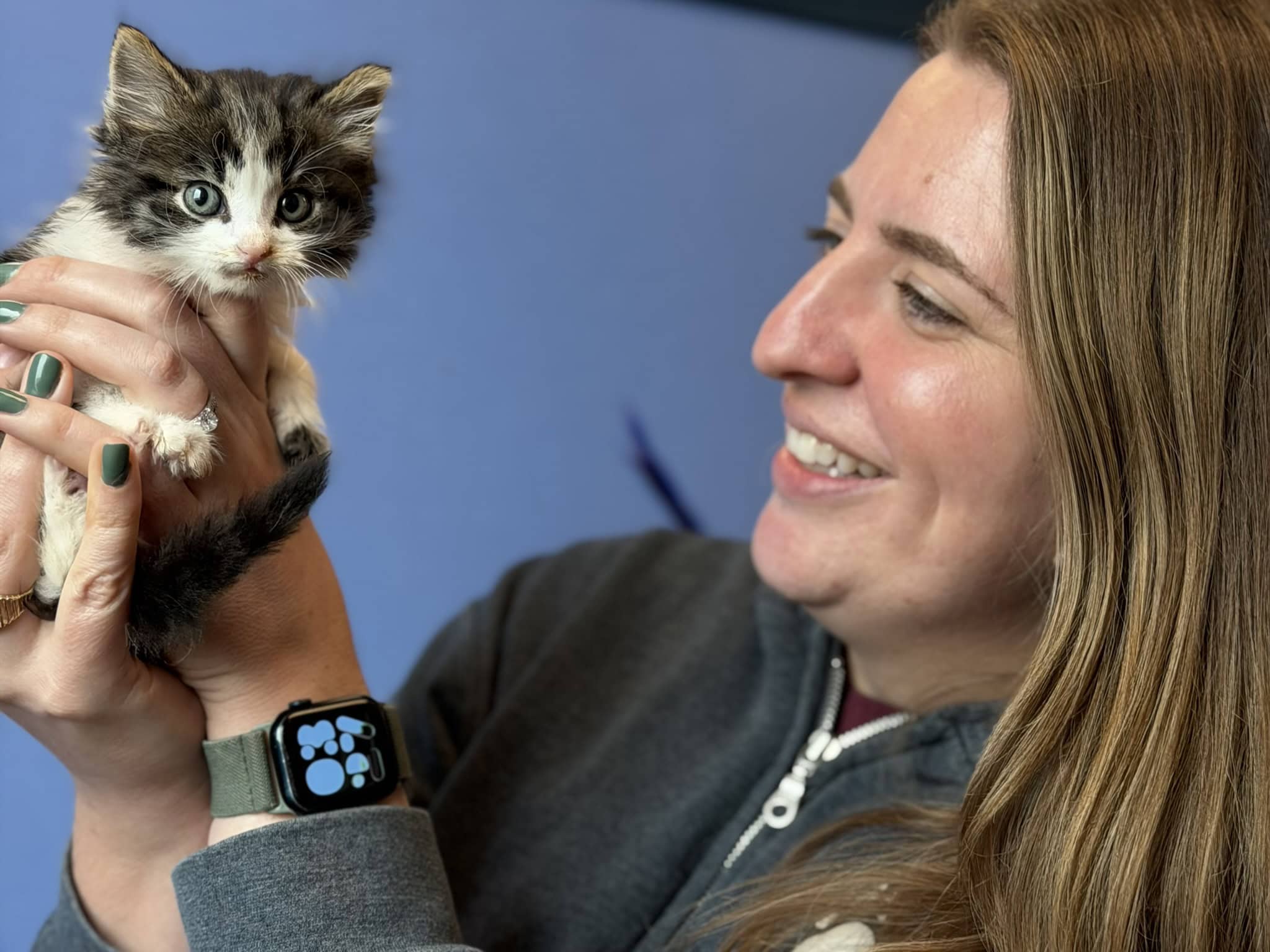 woman smiles while holding kitten